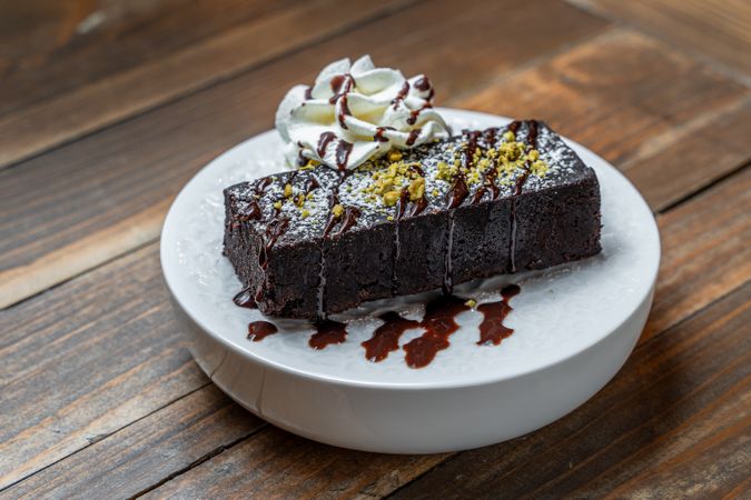 Decadent chocolate brownie with whipped cream and chocolate drizzle