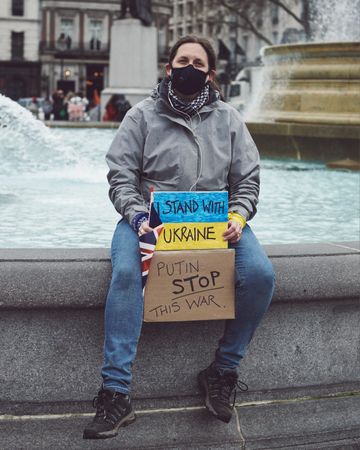London, England, United Kingdom - March 5 2022: Woman sitting at fountain with anti war sign