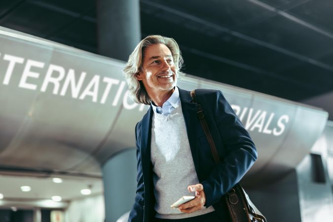Happy business traveler walking at international airport