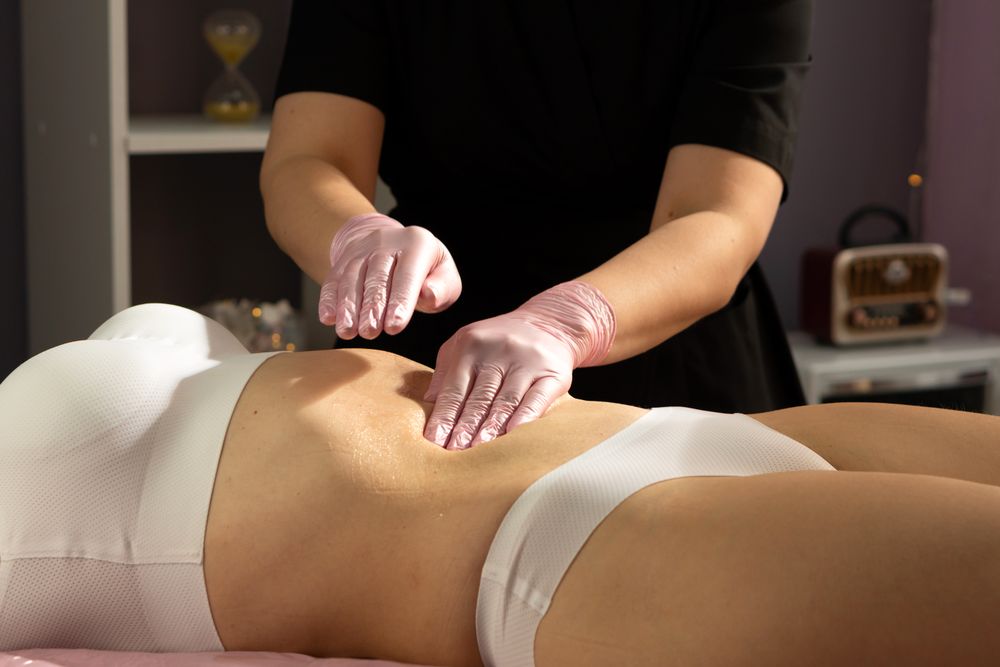 Gloved hands gently massage abdomen after honey application.