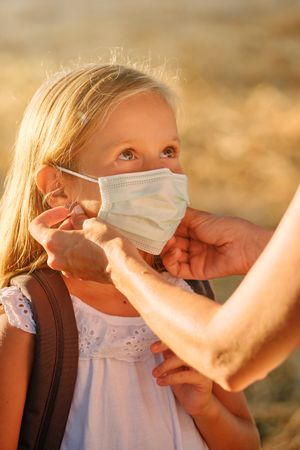 Unrecognizable person putting mask on girl
