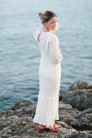 Romantic woman touching hair on rocky seashore