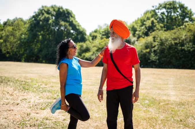 Mature Sikh couple stretching in field