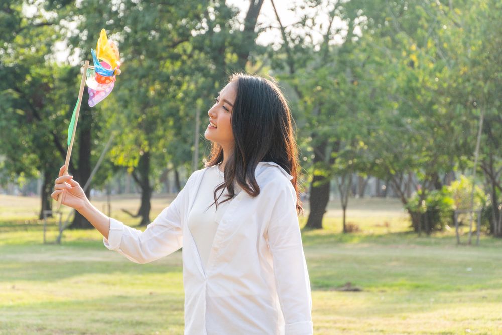 Woman gazing at colorful wind toy in park