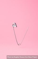 Close up of one opened safety pin on pink background bGM6v5