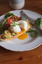 Slice of bread with avocado and runny poached egg on top