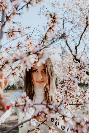 Young happy woman between trees in garden