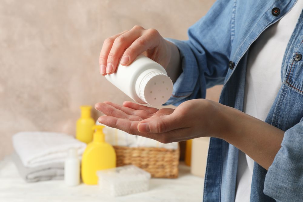 Mom applying talc powder from plastic tube. Baby hygiene