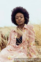 Woman in pink floral robe sitting on brown grass field 0vmARb