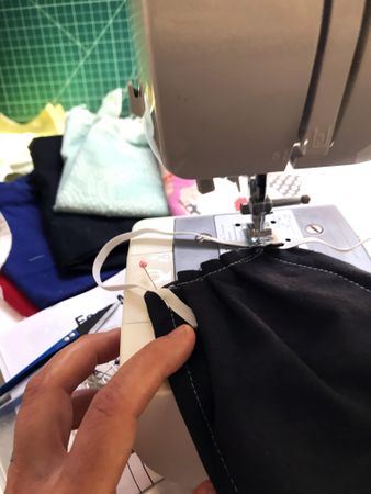 Person sewing fabric face mask on home sewing machine