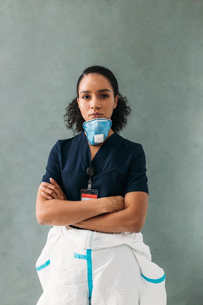 Black female doctor with half removed face mask and hazmat suit
