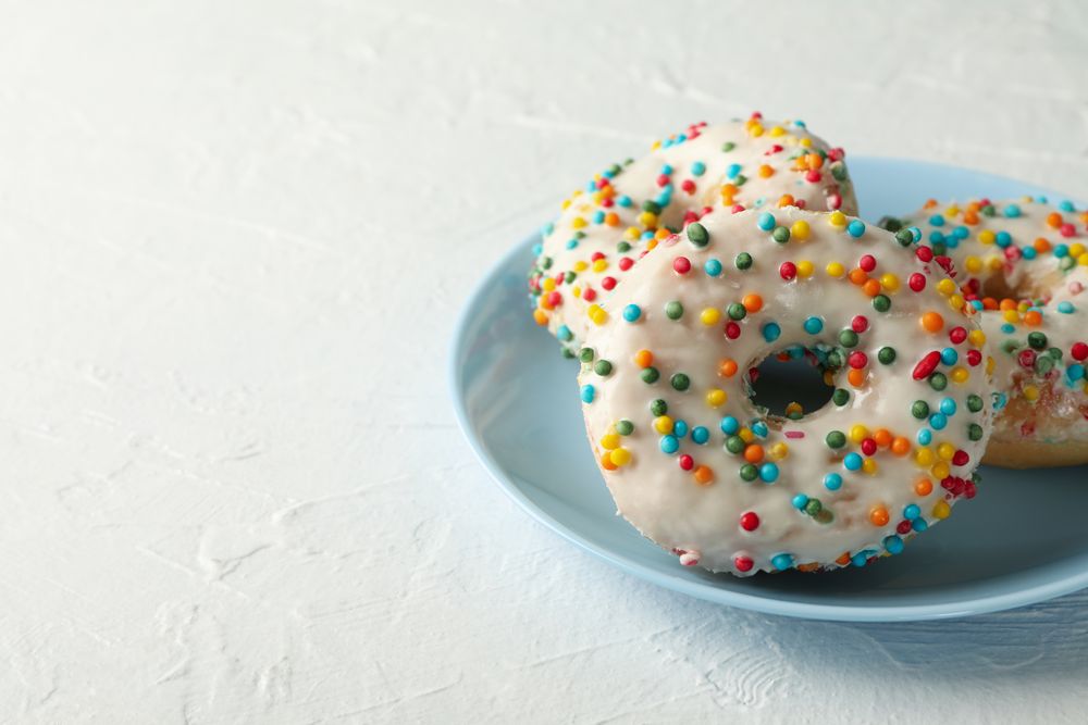 Plate with tasty donuts on plain background