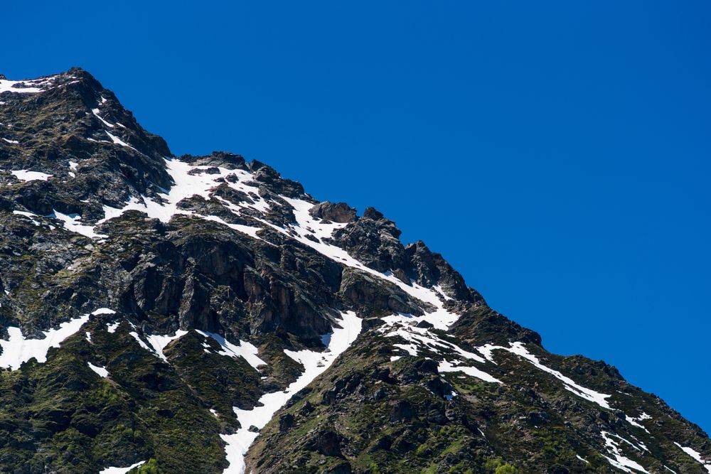 Snow-covered mountain peak with green forested slopes below.