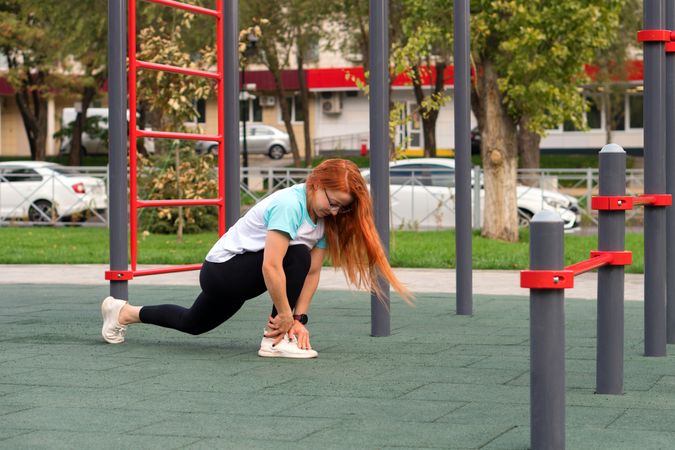 Woman in lunge stretch at outdoor playground