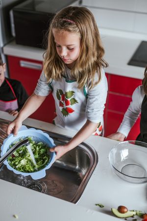 Child washing herbs for salad