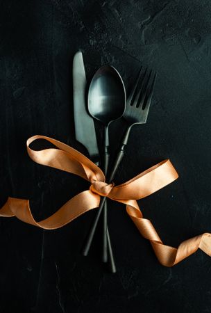 Dark cutlery set wrapped in gold bow