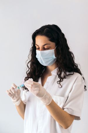nurse portrait with mask injecting serum into a syringe