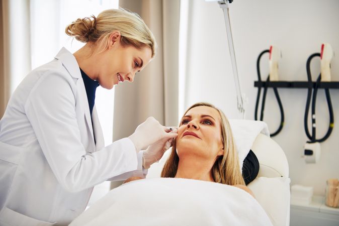 Female dermatologist performing treatment on patient’s face