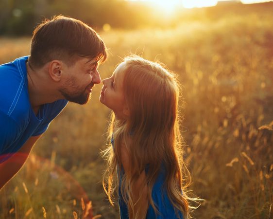 Playful man and daughter  dressed in blue in sunny field