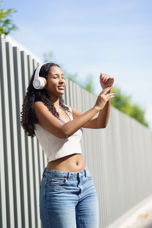 A Joyful Young Woman Dancing Outdoors with Headphones, Embracing the Freedom of Movement