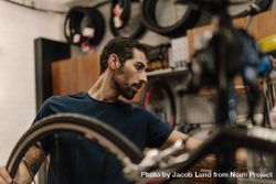 Side view of man fixing bicycles in repair shop 5krOj0