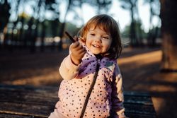 Joyful girl showing stick at camera in park
