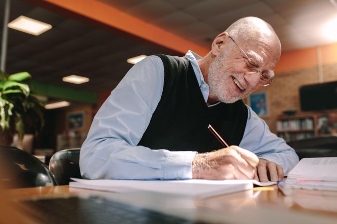 Cheerful older man studying and sitting in a university classroom