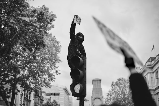 London, England, United Kingdom - June 6th, 2020: Man atop traffic light with sign