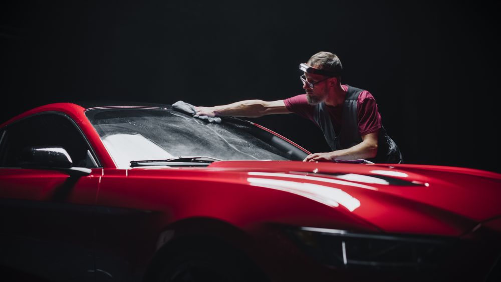 Automotive Detailer Polishing a Car Windshield with a Microfiber Towel.