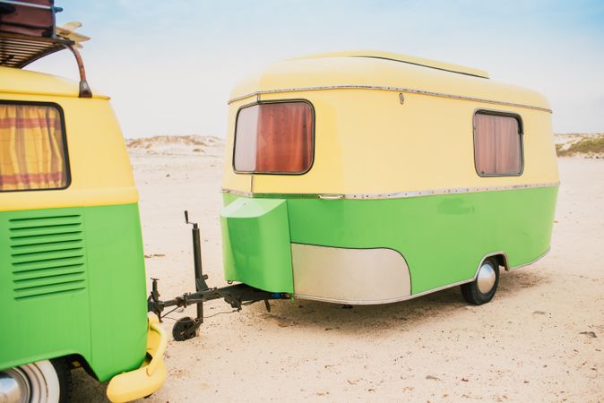Colorful minibus with trailer parked on sandy shore in sunny day
