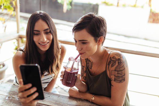 Two females at a restaurant looking at a mobile phone