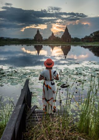 Woman standing at lakeside and enjoying view of Buddhist temples