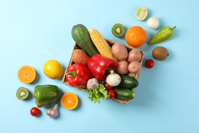 Wicker basket and vegetables on blue background, copy space
