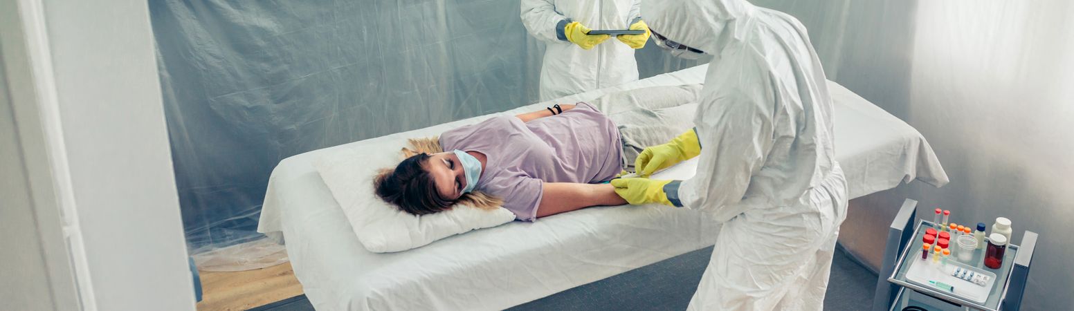 Doctors taking blood sample from patient lying on a gurney
