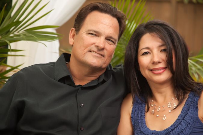 Smiling Couple Sitting In Front of Fern
