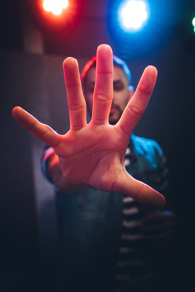 Man dancing in spotlight outstretching hand forward