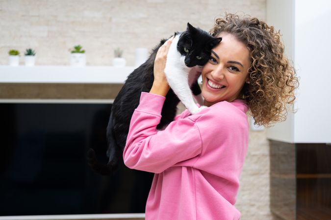 Happy woman embracing adorable cat at home
