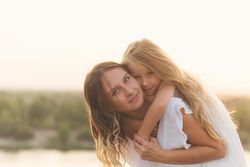 Little girl on mother’s back with a river in background