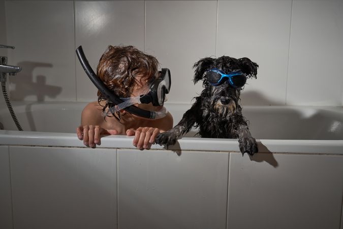 Boy in diving mask with dog in bathtub