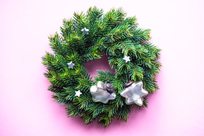Christmas wreath with decorative stars on pink background