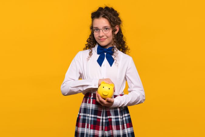 Girl holding yellow piggy bank