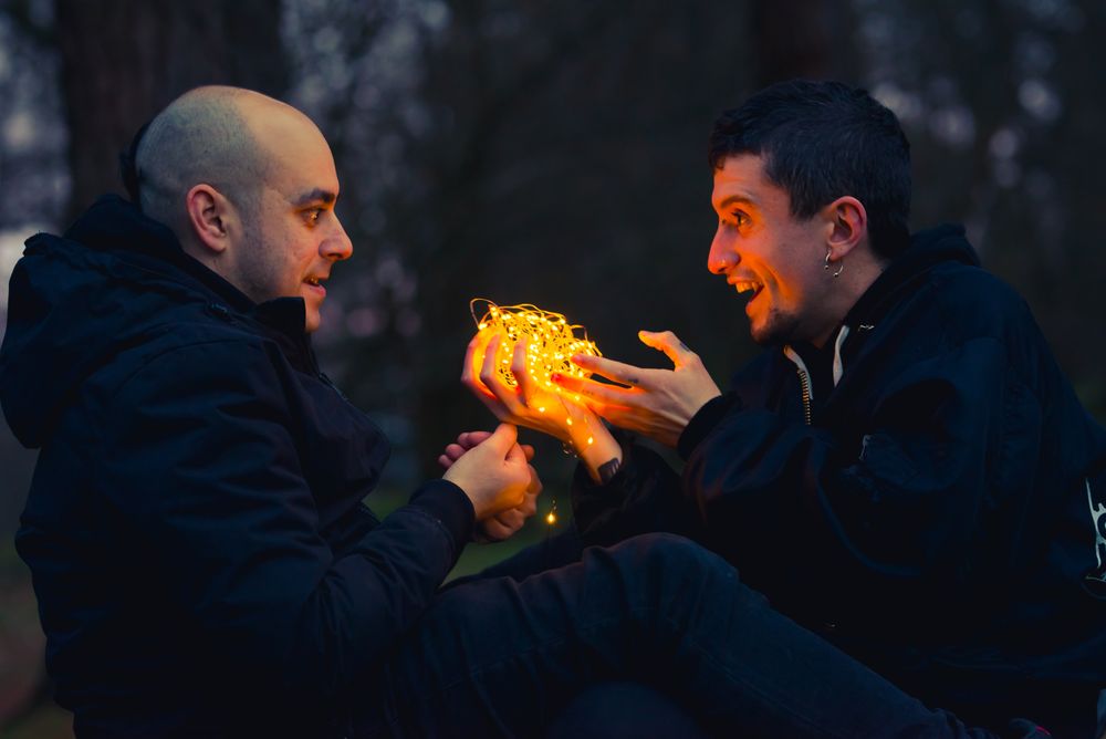 Men holding fairy lights near dog in forest at night