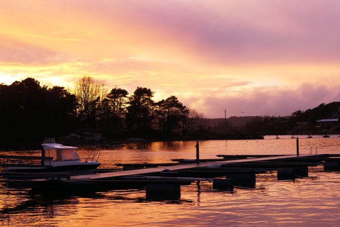 Boat by pier in twilight and distant forest silhouette