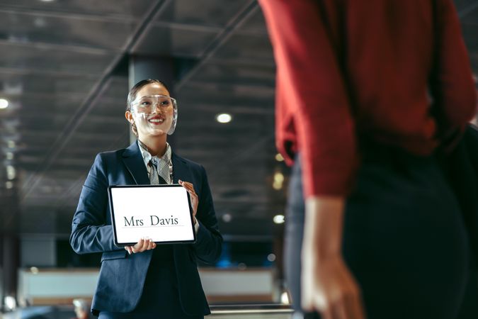 Female chauffeur with a sign at airport arrival gate