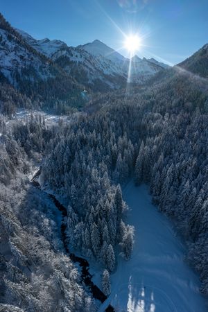 Aerial view with snowy forest and mountain river in the Bavarian Alps