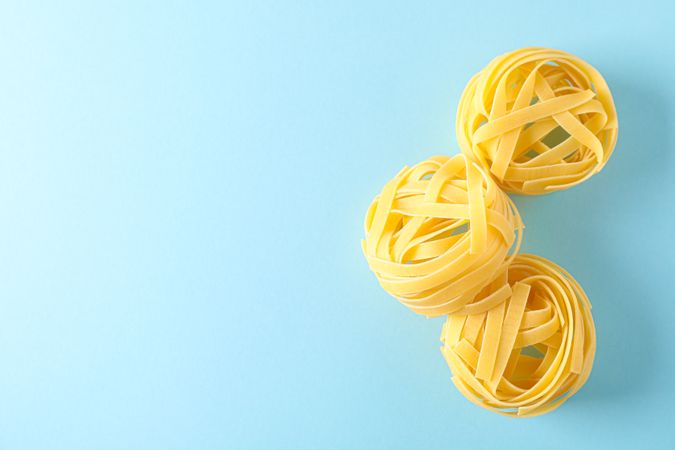 Pasta on color background, space for text. Dry raw whole pasta