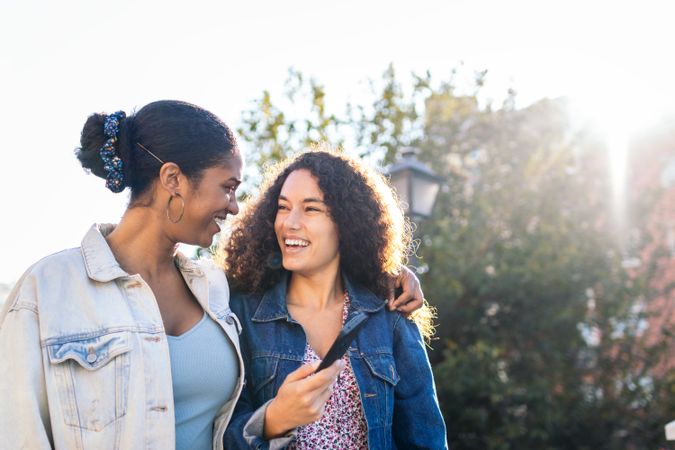 Black Latina friends using a smartphone in the park.