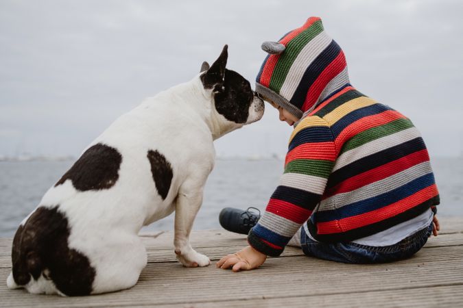 Anonymous kid petting dog on pier