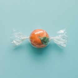 Orange wrapped like candy on bright blue background