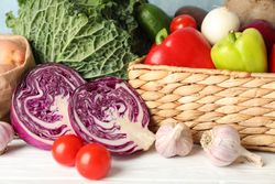 Wicker basket and vegetables on wooden background, close up